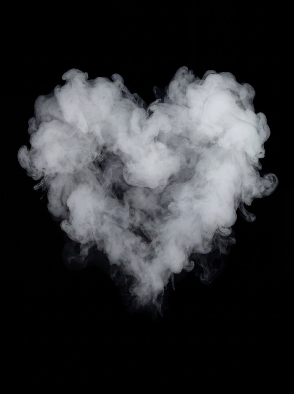 A heart-shaped formation of dense white smoke against a stark black background.