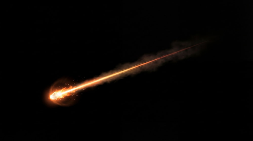 A single, bright orange meteor streaks across a black background, leaving a glowing trail of fire and smoke.