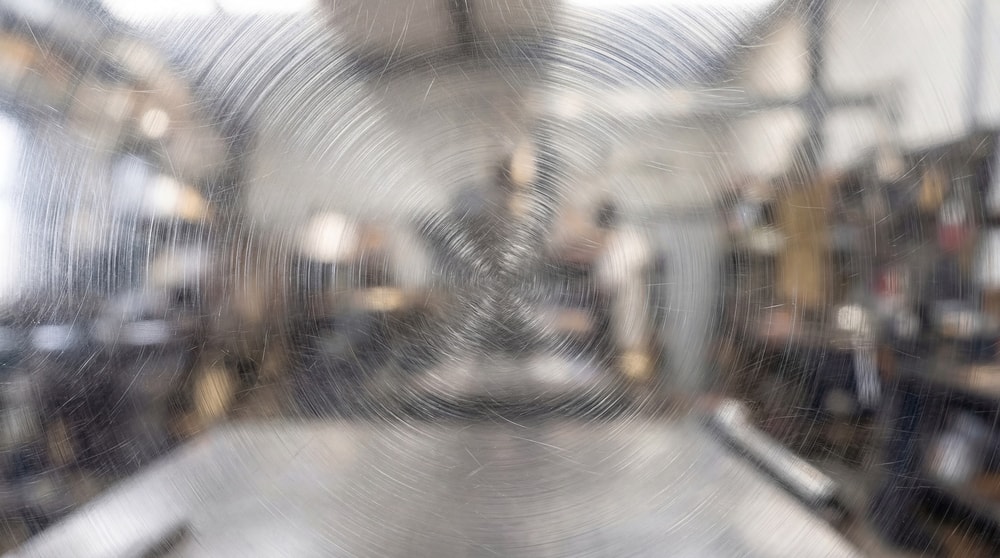 Close-up view of a metal surface featuring distinct radial circular scratch patterns and a brushed finish