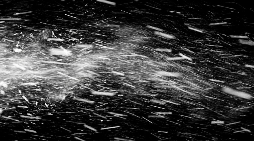 Dense, wind-driven snowfall with prominent, large white streaks against a black background.