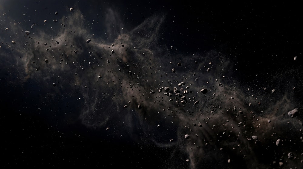 A dense cloud of jagged asteroid fragments and dust against a black, star-filled background.