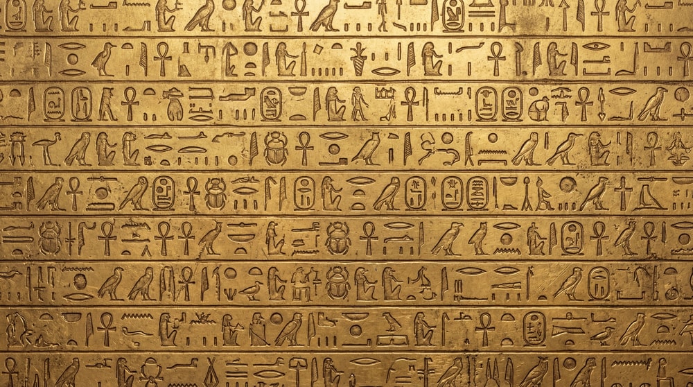 Close-up of a golden surface intricately carved with Egyptian hieroglyphs.