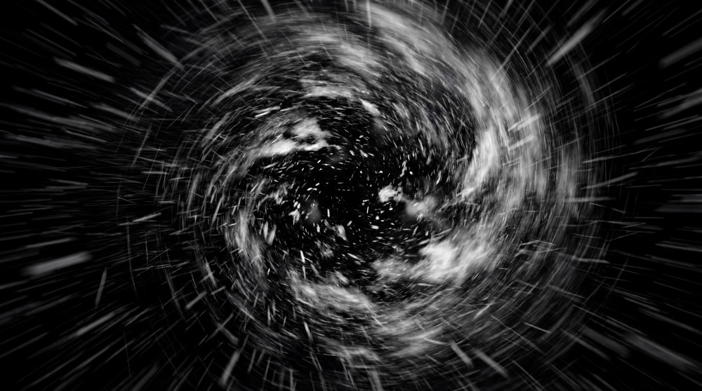 A dynamic, high-intensity snowfall depicted as a swirling vortex against a stark black background, with streaks of white suggesting rapid motion.