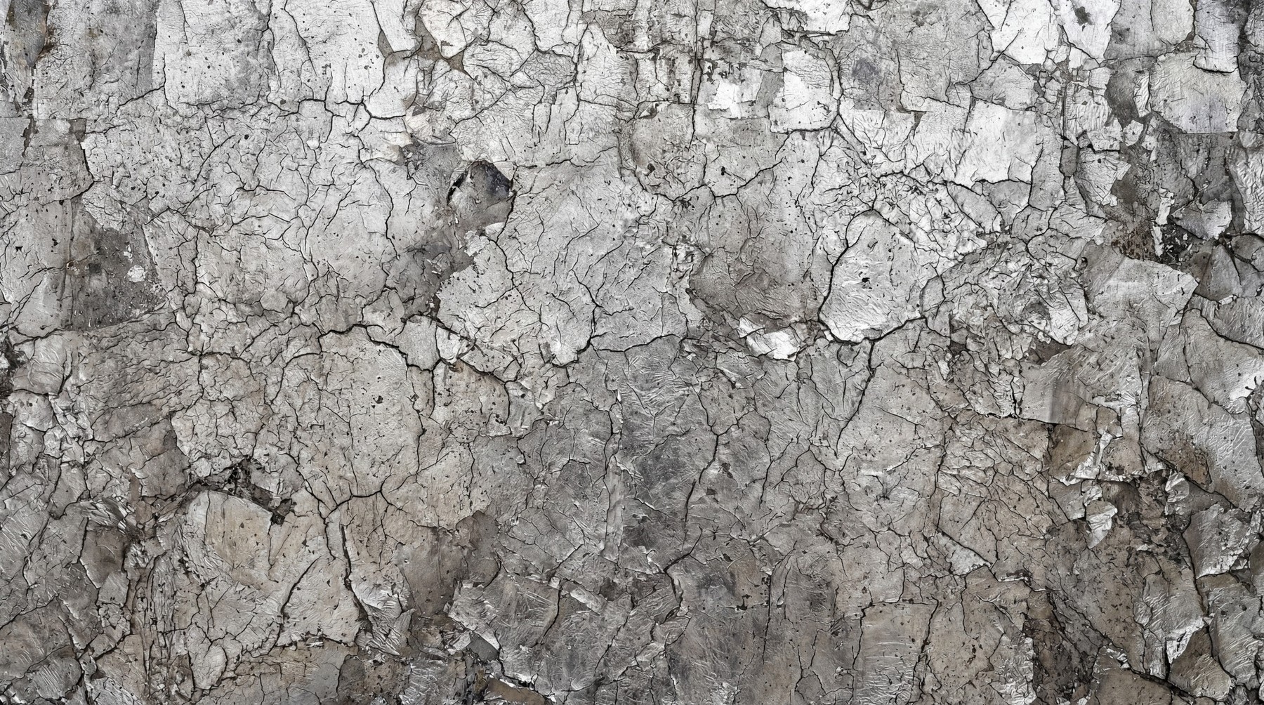 Close-up of a weathered metal surface with heavily cracked and peeling gray paint revealing layers of underlying industrial material.