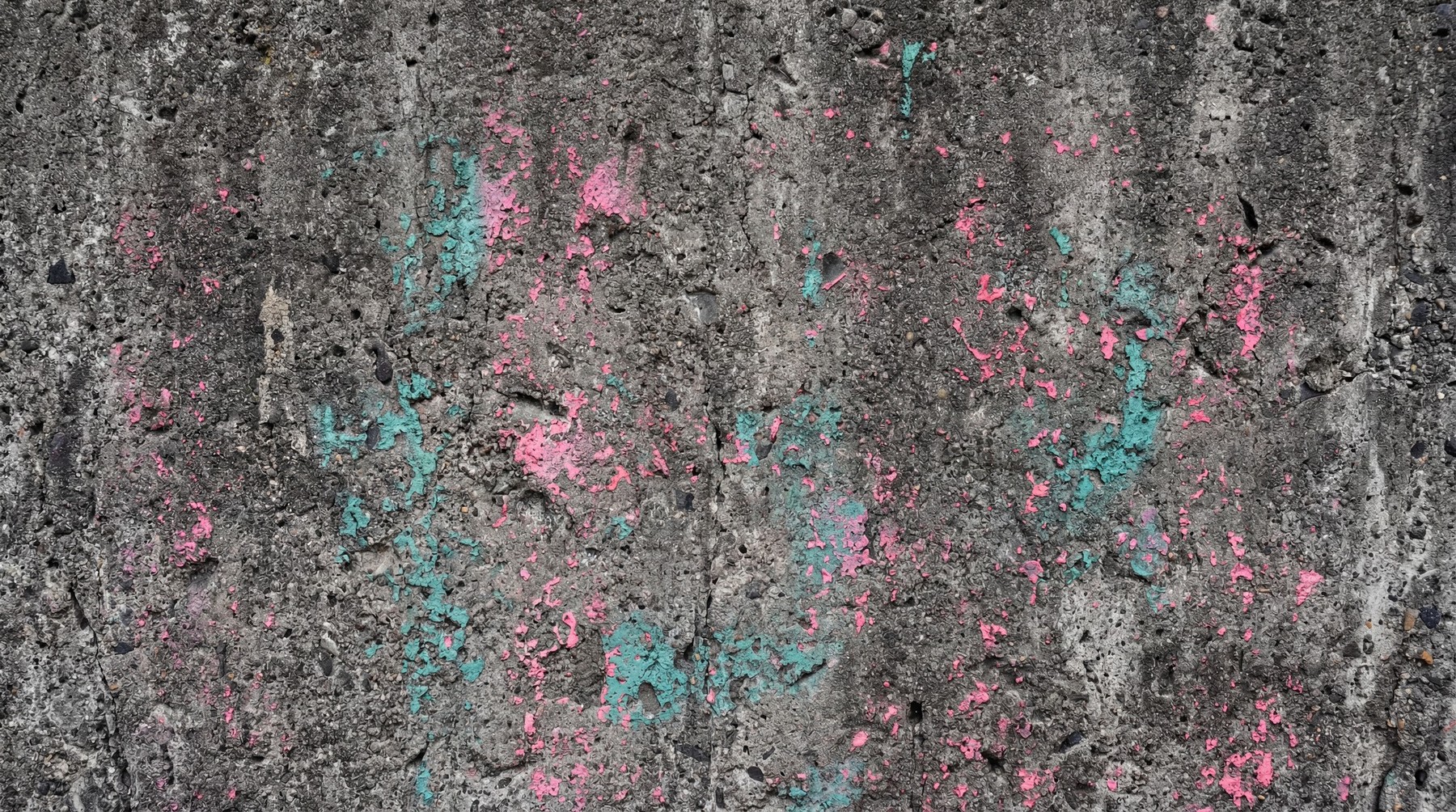 A rough, grey concrete wall texture with scattered patches of peeling pink and teal paint.