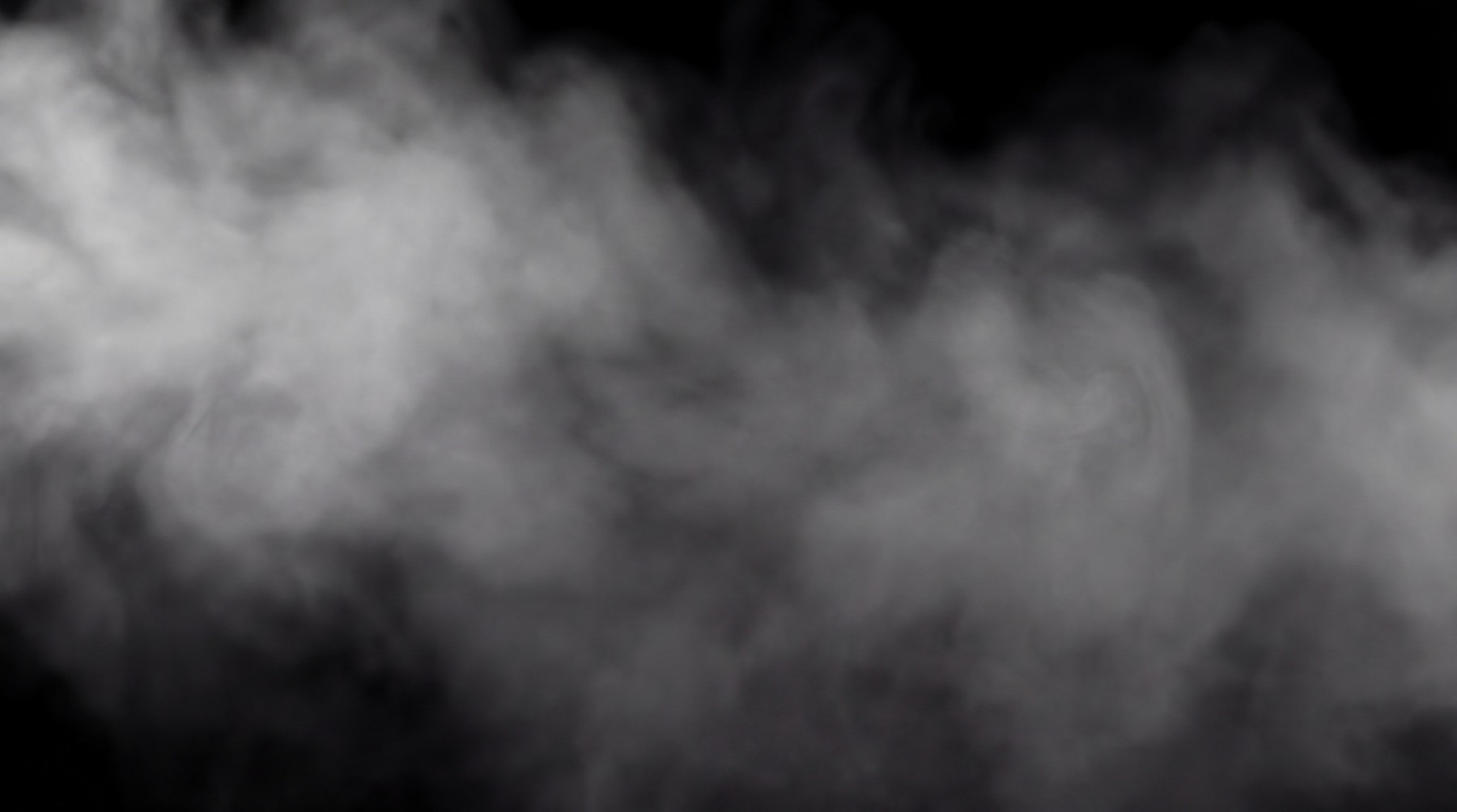 A horizontal stream of soft, wispy mist or fog, rendered in shades of grey against a pure black background.