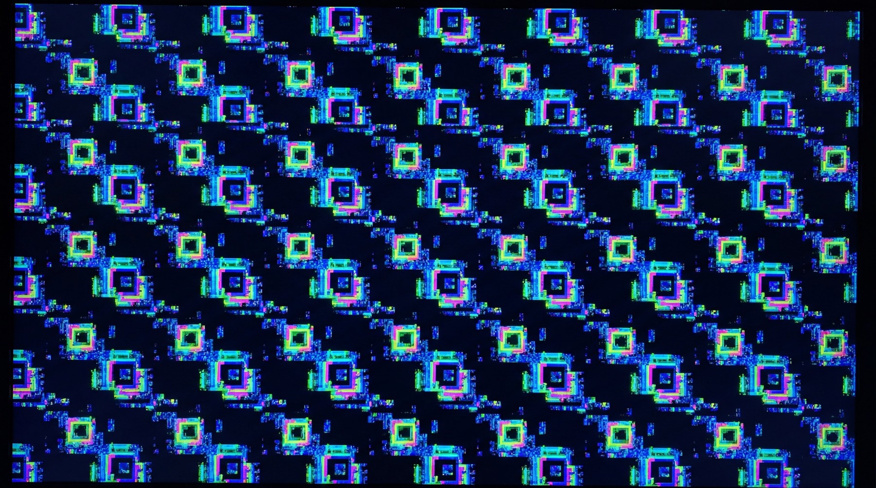 A chaotic overlay of vibrant, pixelated squares in blue, green, and pink, resembling a GPU kernel panic screen.