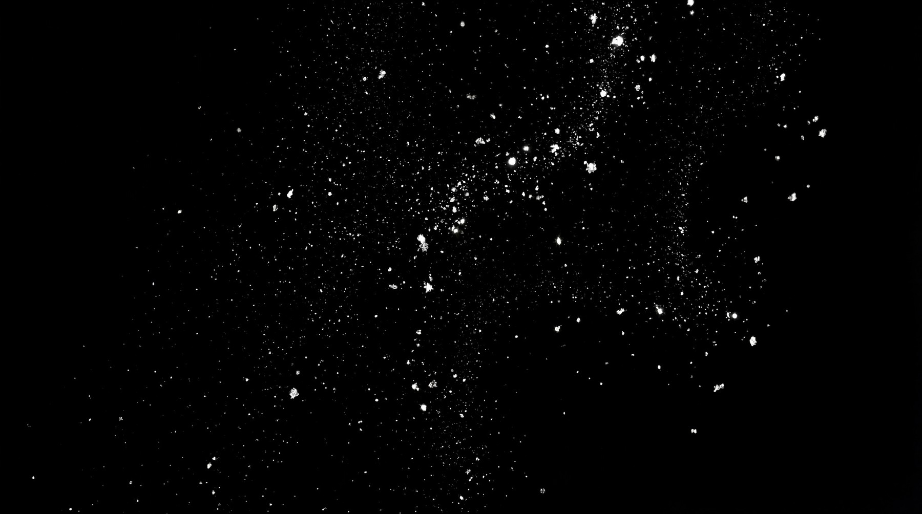 A monochromatic overlay of scattered fine dust particles against a black background.