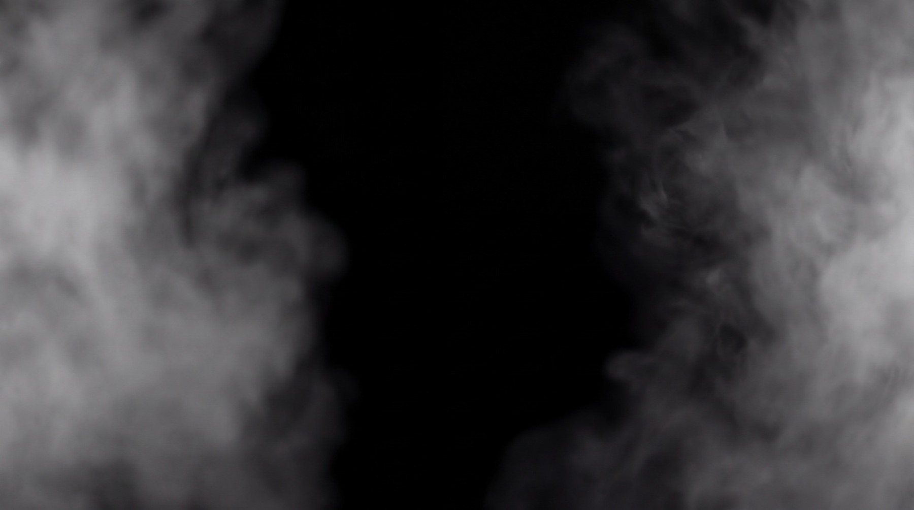 A wispy, swirling fog formation with dense central mass and lighter edges, set against a pure black background.