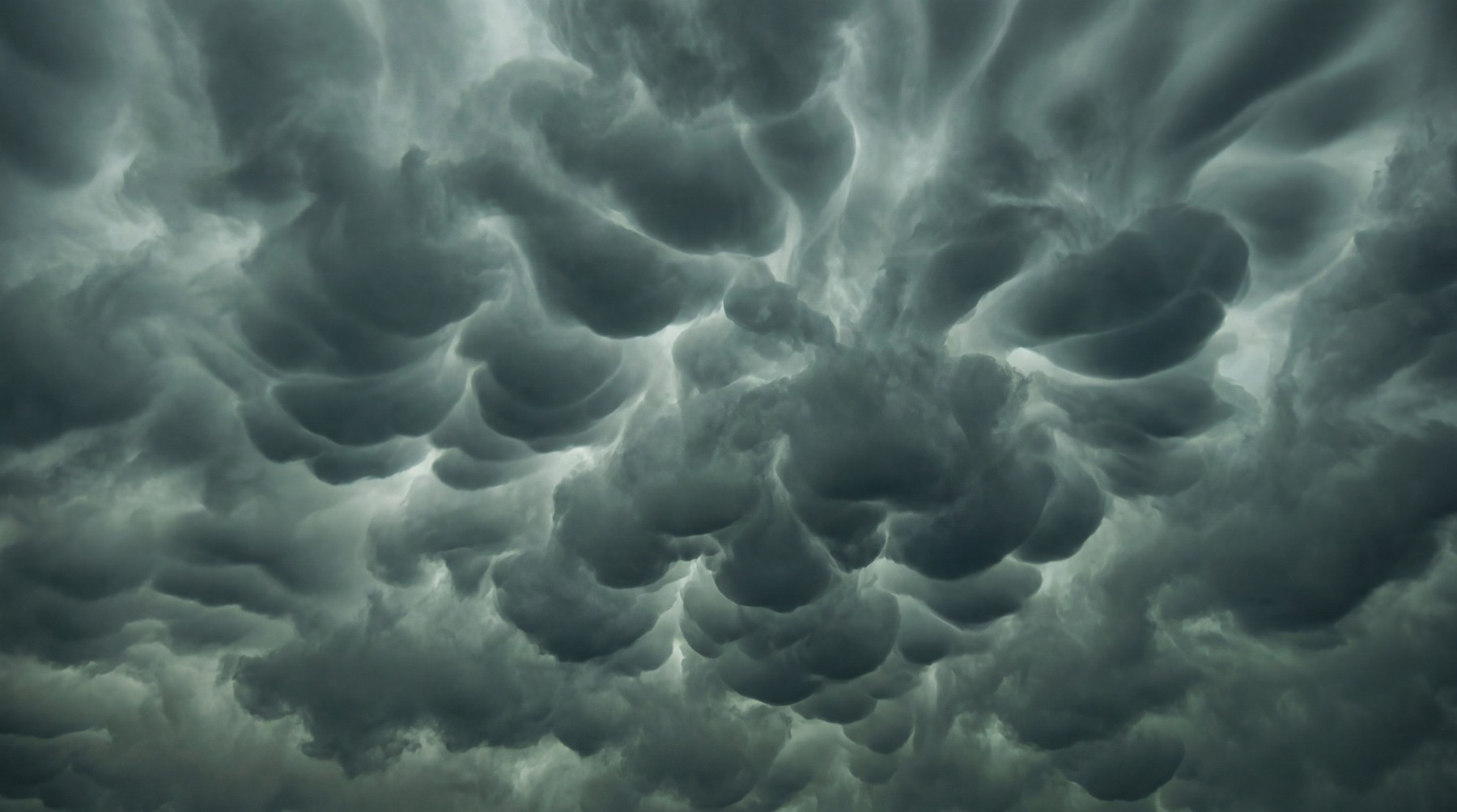 A dramatic sky filled with dark, ominous mammatus clouds, creating a textured, undulating pattern.