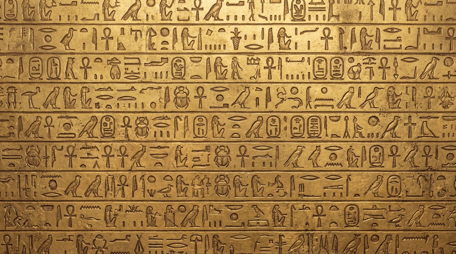 Close-up of a golden surface intricately carved with Egyptian hieroglyphs.