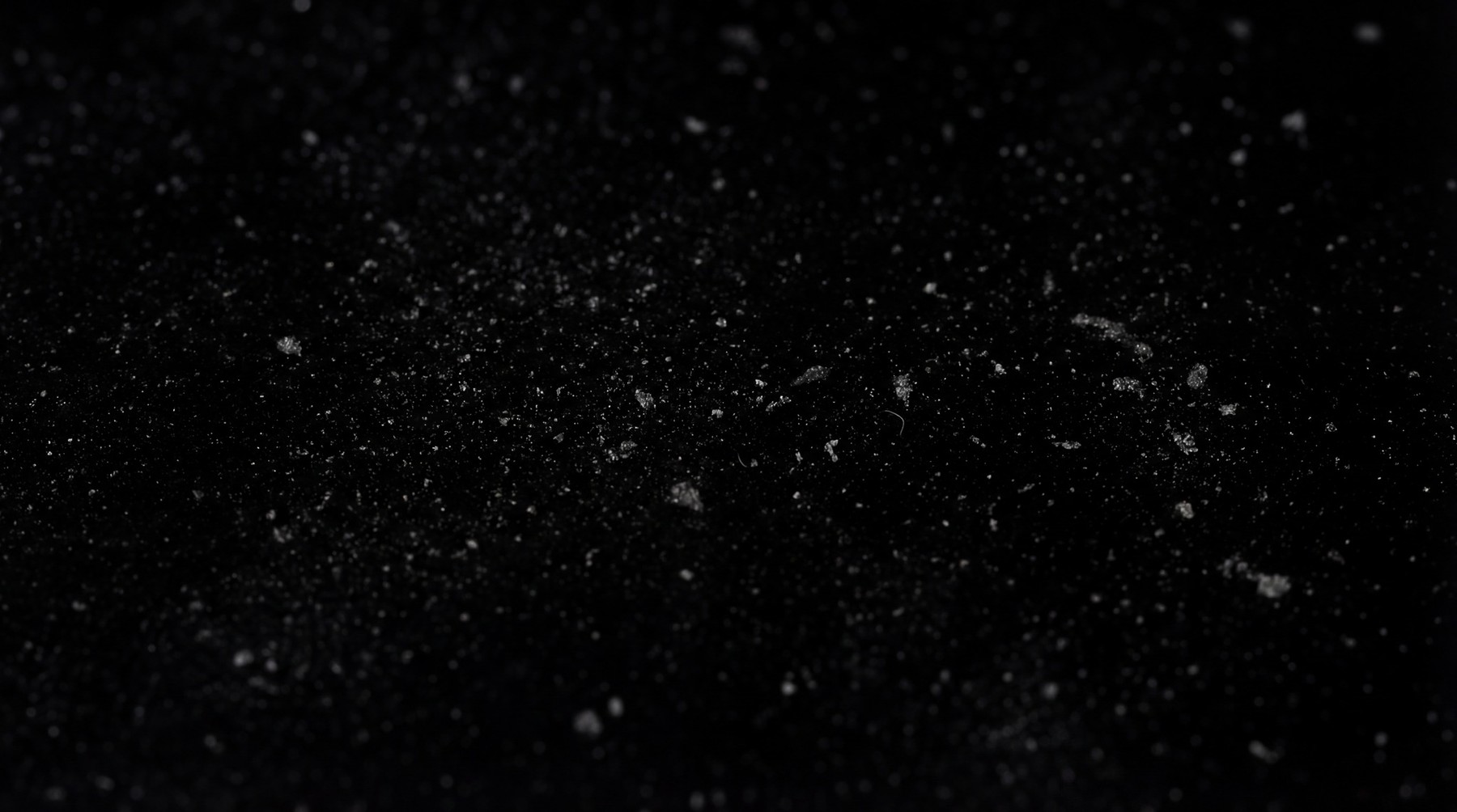 A high-resolution overlay of fine, light-colored dust particles scattered across a black background.
