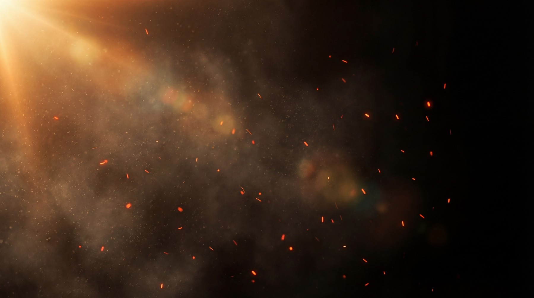 A dark background illuminated by dramatic golden light rays from the upper left, casting a warm glow on swirling atmospheric dust particles and numerous small, bright red sparks.