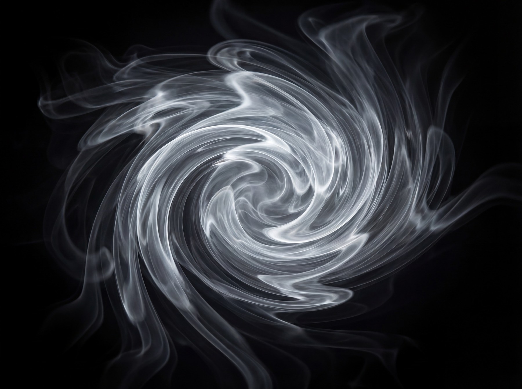 A dynamic vortex of white smoke with a dark background, swirling clockwise.