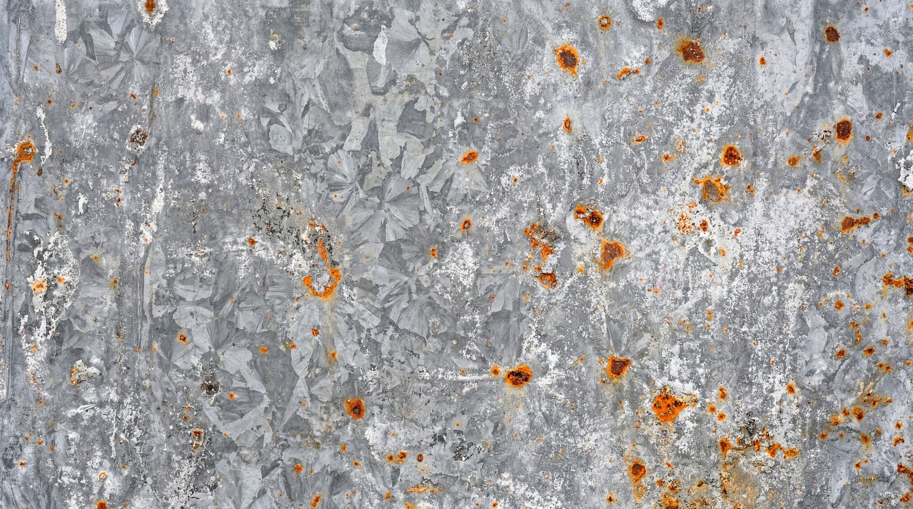 Close-up of galvanized steel with scattered, pitted orange rust.