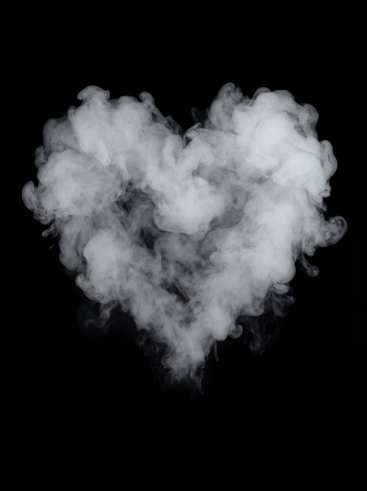 A heart-shaped formation of dense white smoke against a stark black background.