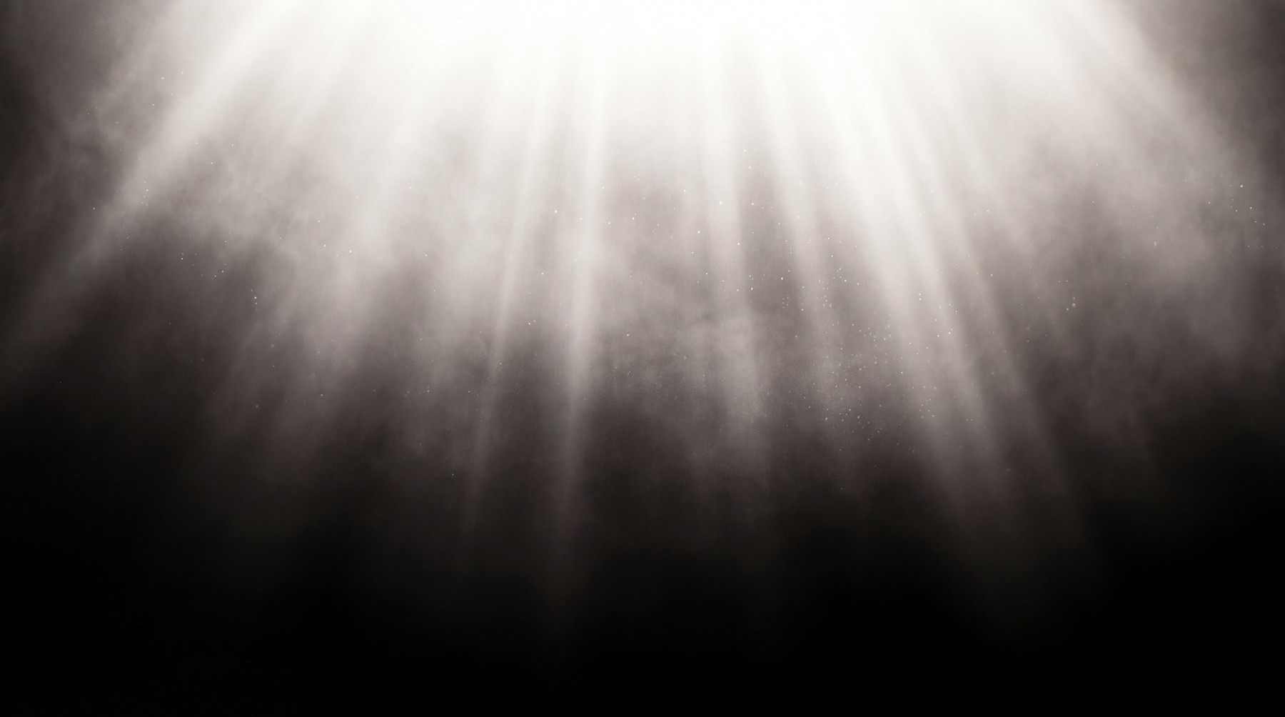 A dark background with bright, ethereal light rays shining downwards through a smoky, particle-filled haze.