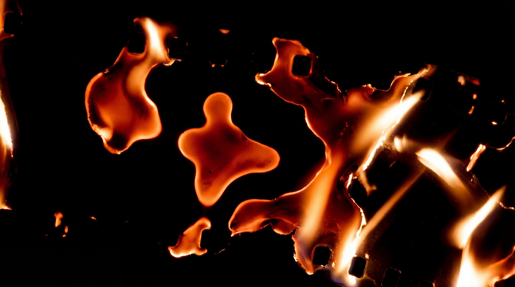 Abstract orange and yellow flames and burnt paper edges on black background, suitable for screen blending.