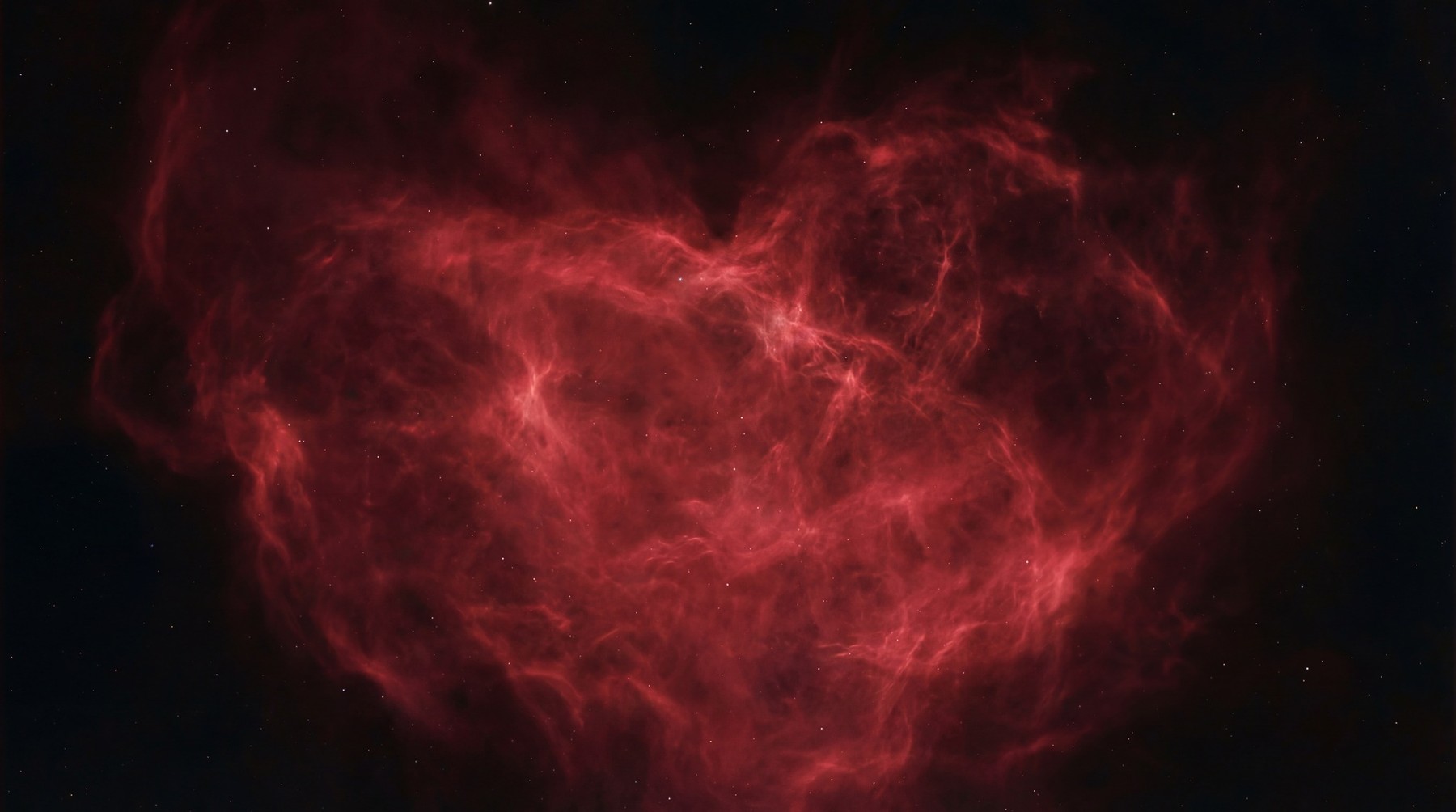 A vibrant red nebula shaped like a heart against a dark, star-filled void.