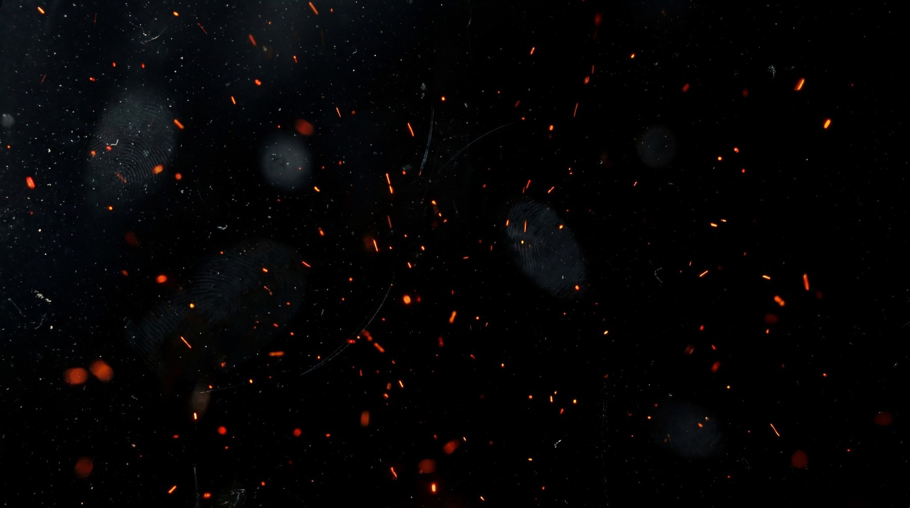 Abstract background with numerous small, glowing red-orange embers and soft, out-of-focus light bokeh circles against a dark backdrop.