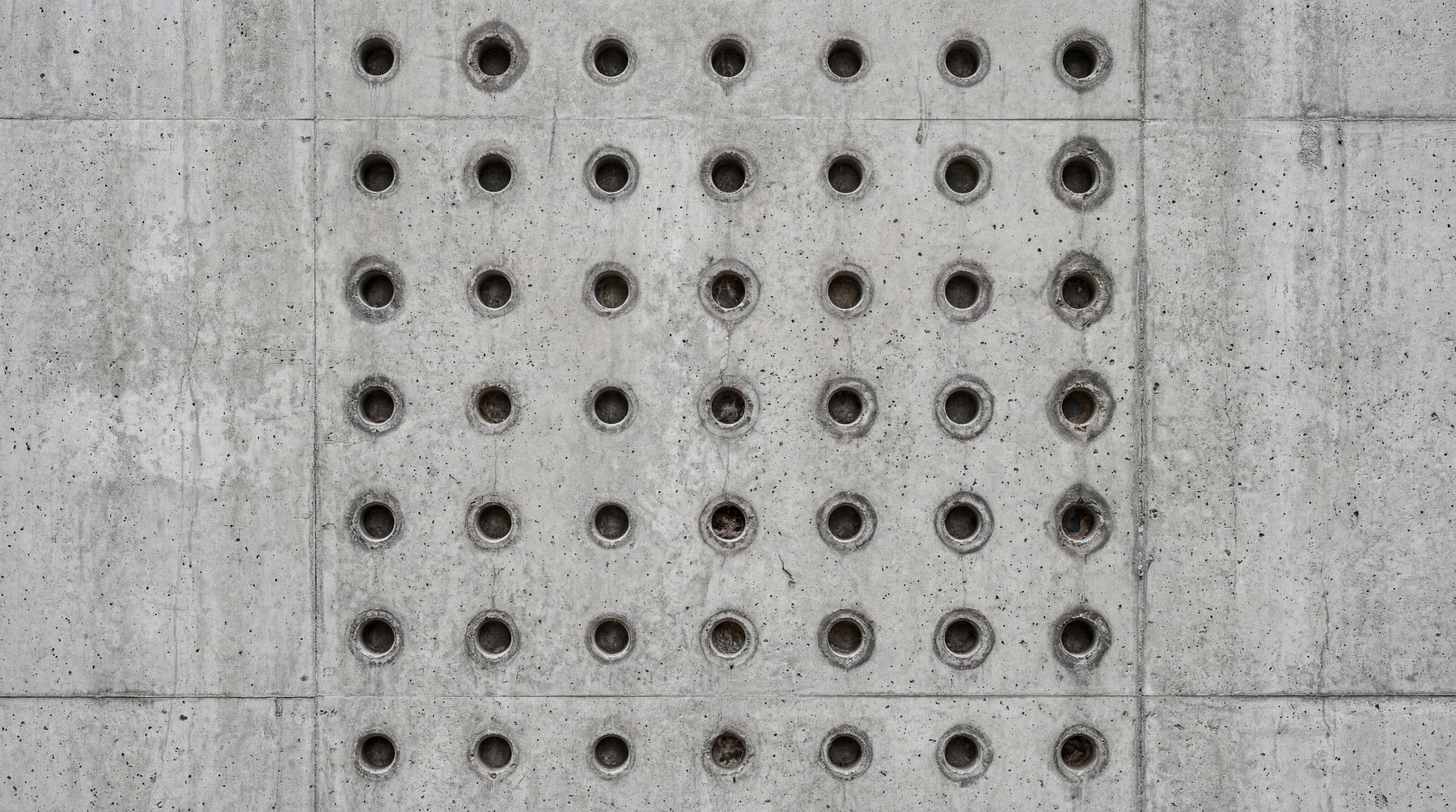 A seamless 4K texture of raw brutalist concrete with a grid of circular indentations.