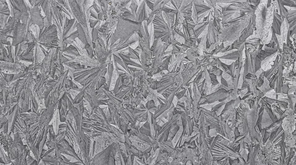 Close-up view of a galvanized steel sheet featuring a distinctive spangle crystal pattern in shades of grey.