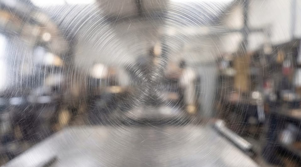 Close-up view of a metal surface featuring distinct radial circular scratch patterns and a brushed finish