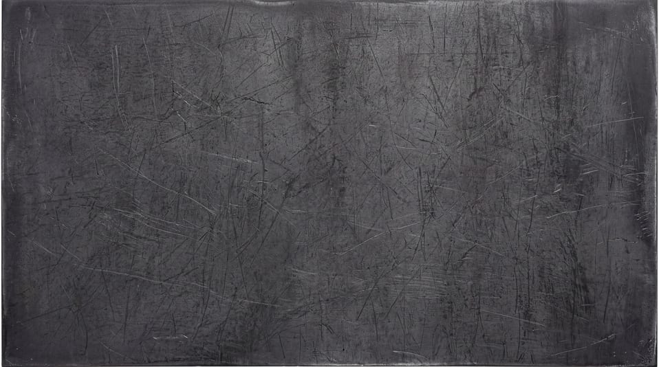A dark, raw steel surface featuring heavy linear scratches and industrial wear across the entire metallic texture.